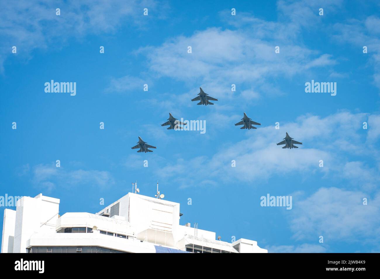 Velivolo militare che vola alto nel cielo blu con le nuvole, sopra l'edificio. Prestazioni di Airshow. Foto Stock