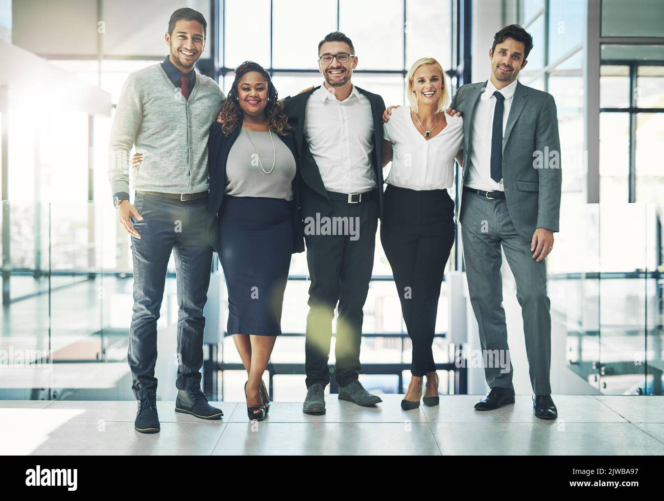 Collaborare è stata una mossa intelligente. Ritratto di un gruppo eterogeneo di colleghi sorridenti in piedi braccio in un ufficio. Foto Stock