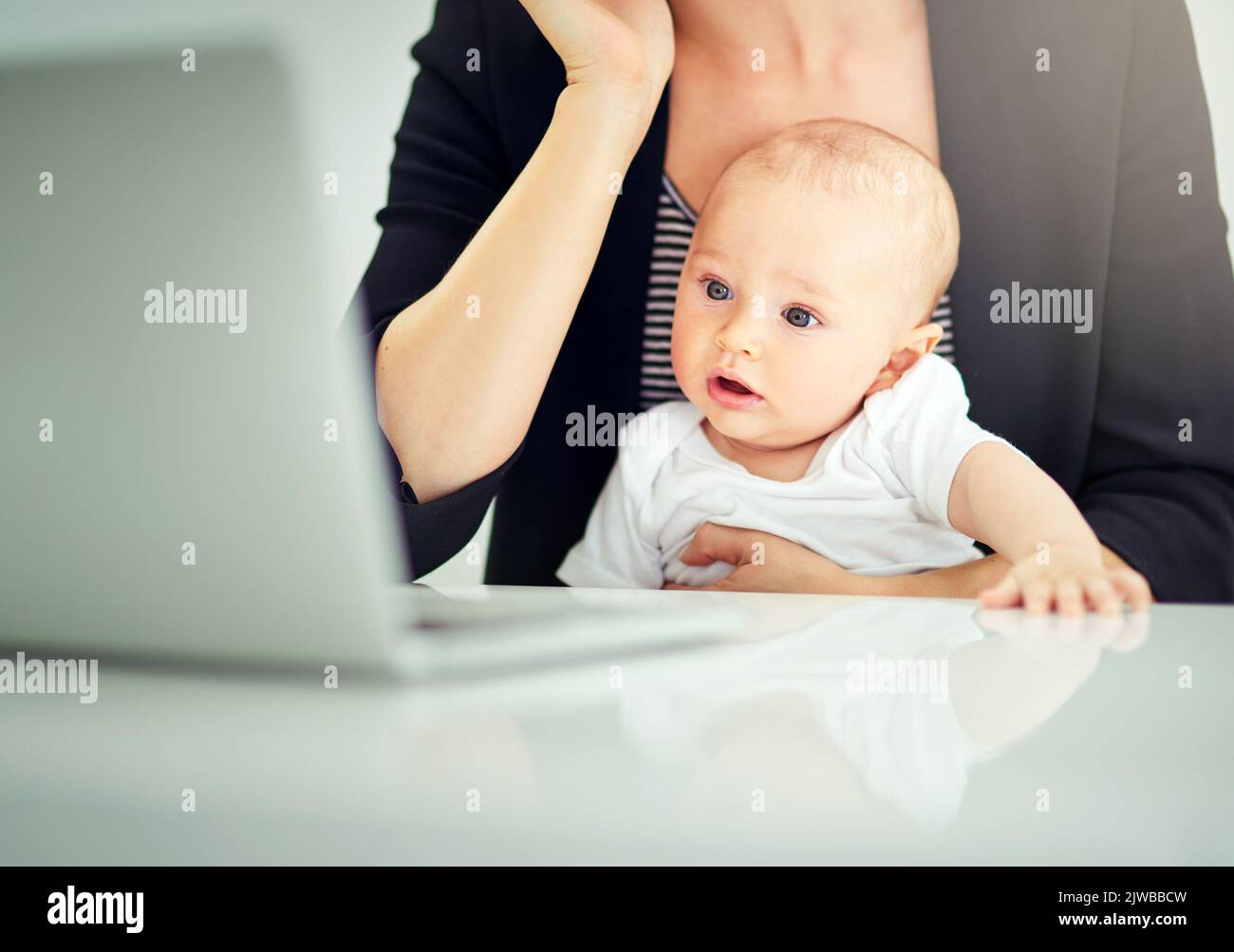 Abbiamo lavoro per fare mamma. Una donna d'affari che si occupava del bambino mentre lavorava sul suo laptop. Foto Stock