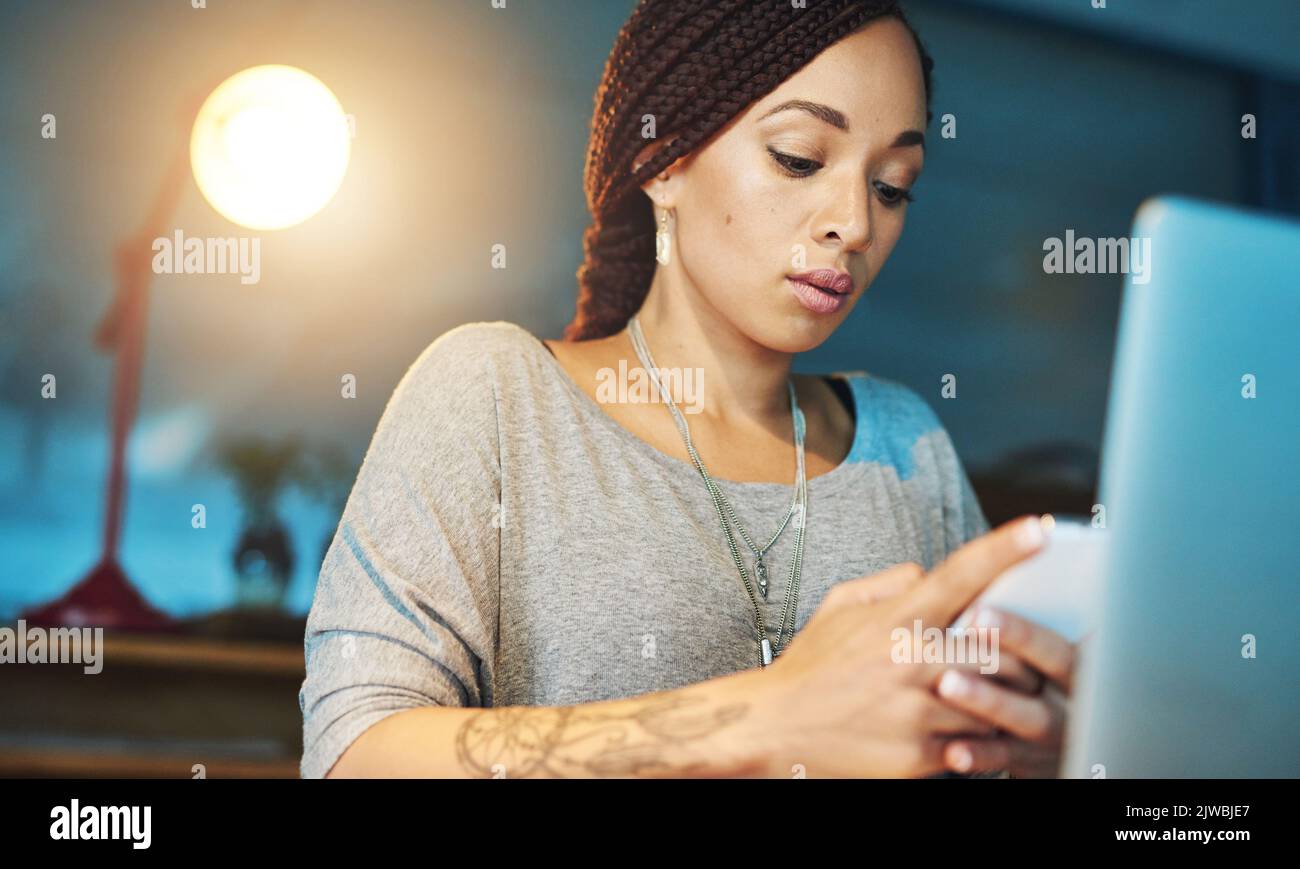 Assicurandosi che rimanga in programma. Una giovane donna che invia un sms mentre lavora tardi nel suo ufficio. Foto Stock