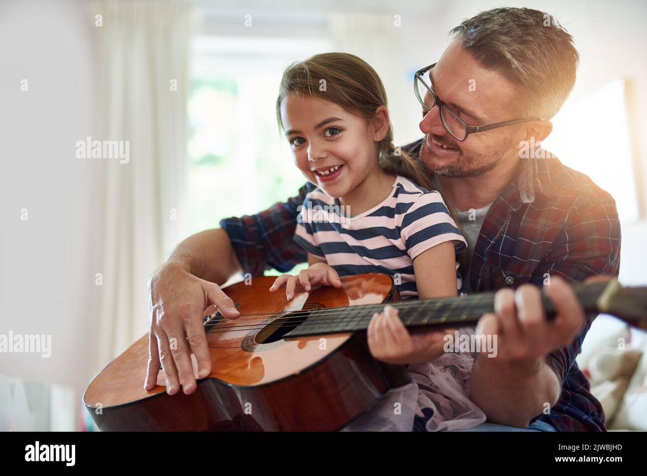 Guardare la sua crescita è la migliore: Una bambina che suona la chitarra con suo padre. Foto Stock