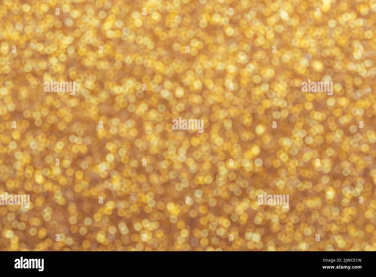 Oro chiaro brillante bokeh sfondo sfocato astratto con brillante sfocatura circolare motivo dorato Foto Stock