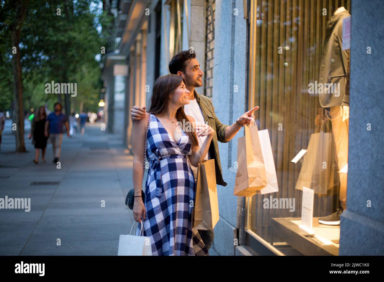 Coppia che guarda in un negozio dalla strada di sera Foto Stock