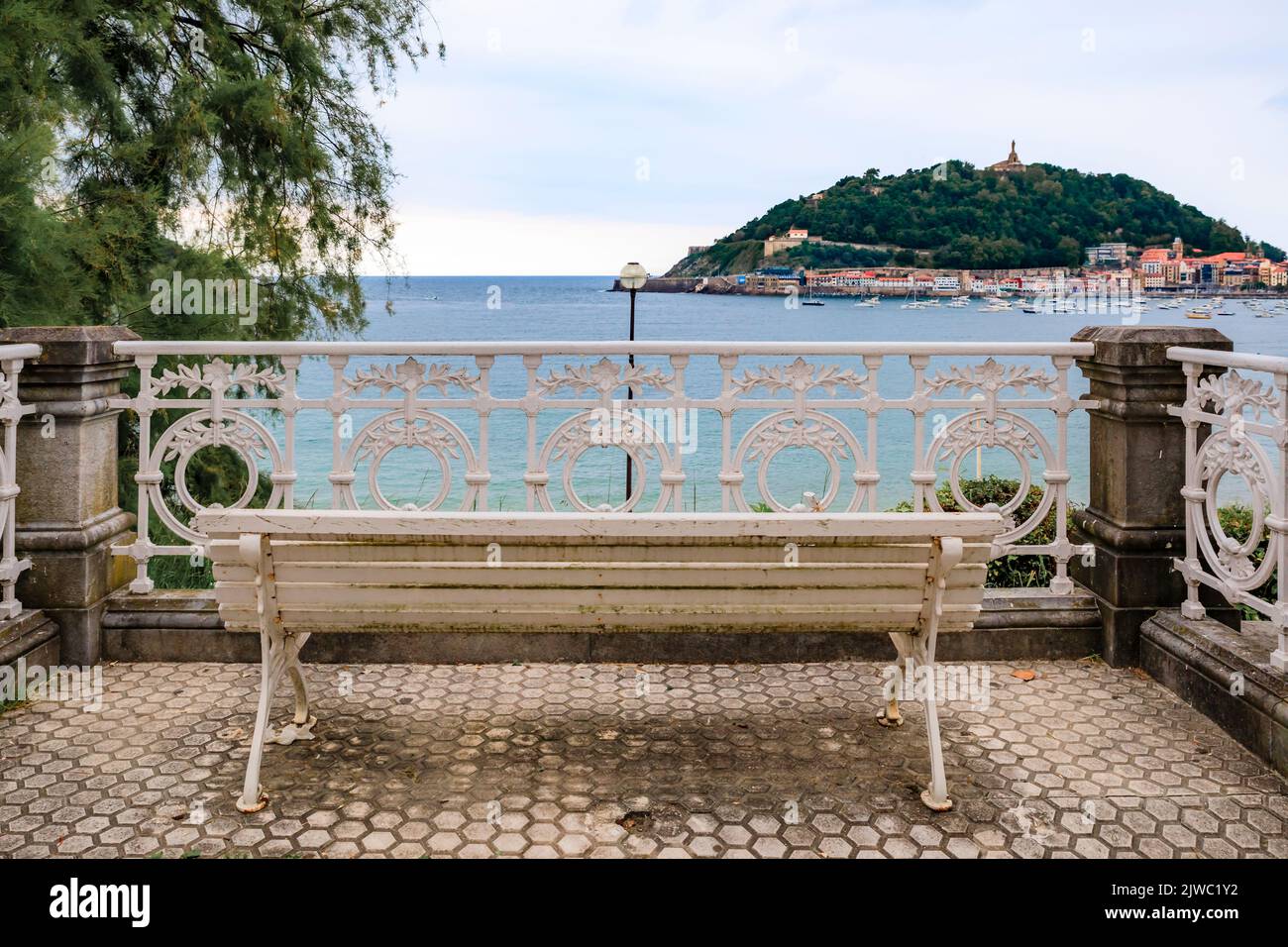 Una panchina che si affaccia sul Paseo de la Concha Promenade e la baia di la Concha e Monte Urgull a San Sebastian, Spagna Foto Stock