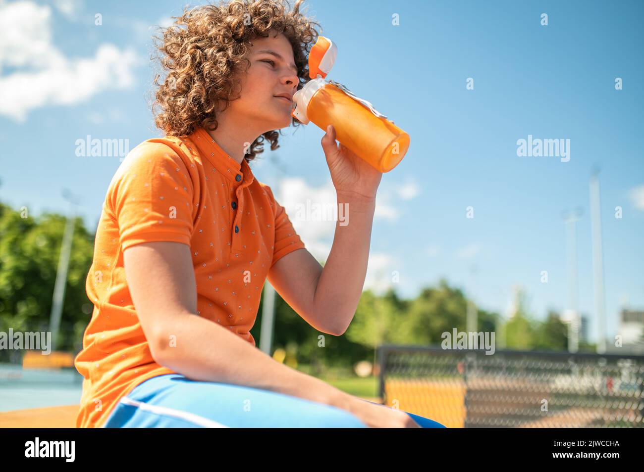 Adolescente ripristinare il suo equilibrio idrico dopo l'allenamento all'aperto Foto Stock