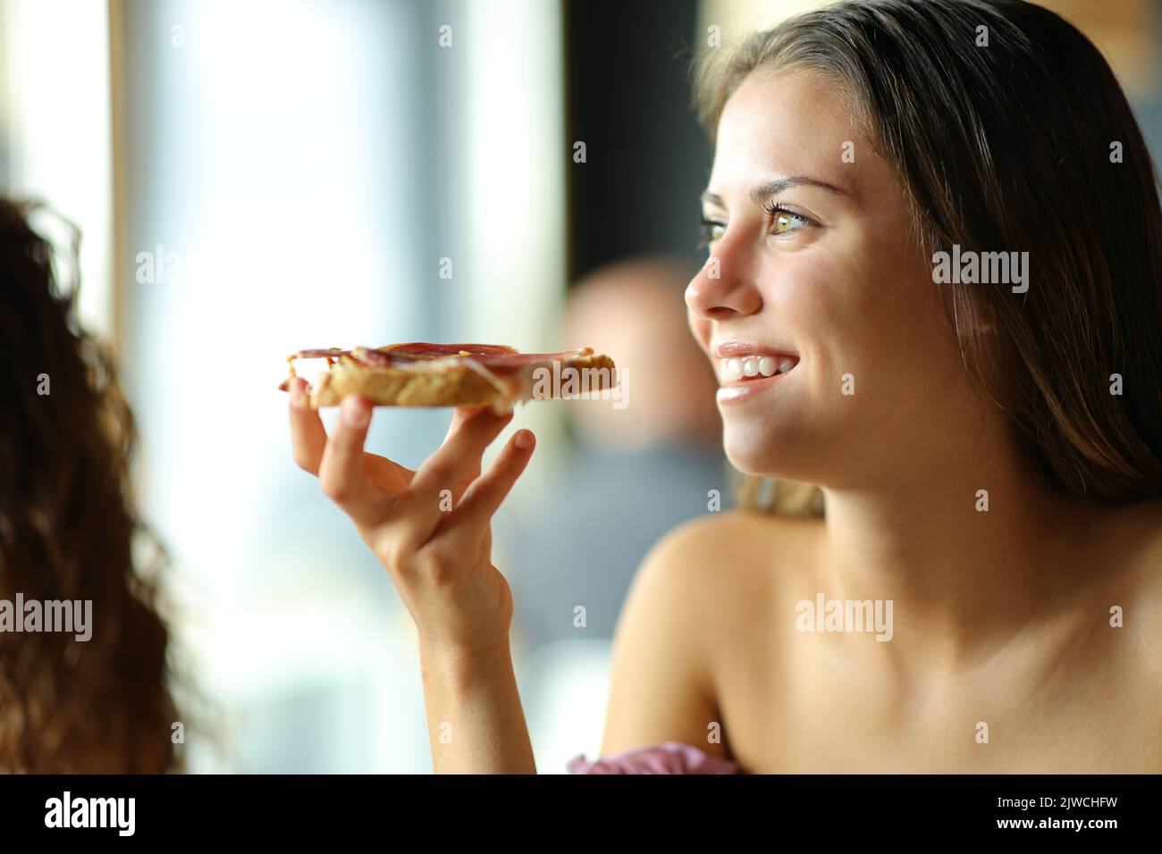 Donna felice che mangia il pane con il prosciutto in un ristorante Foto Stock