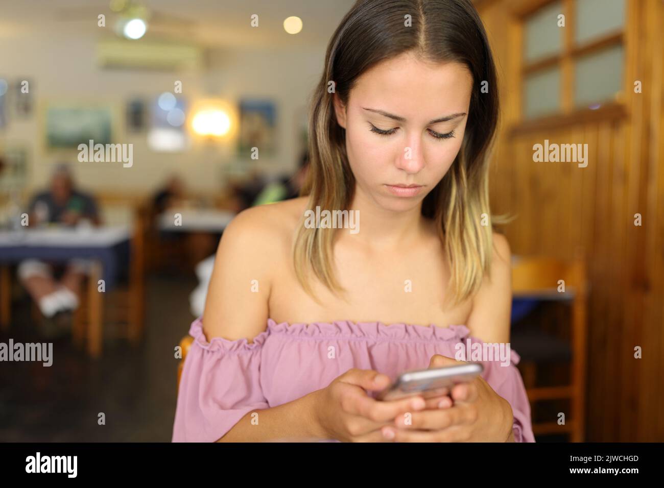 Donna concentrata in un ristorante utilizzando smartphone Foto Stock