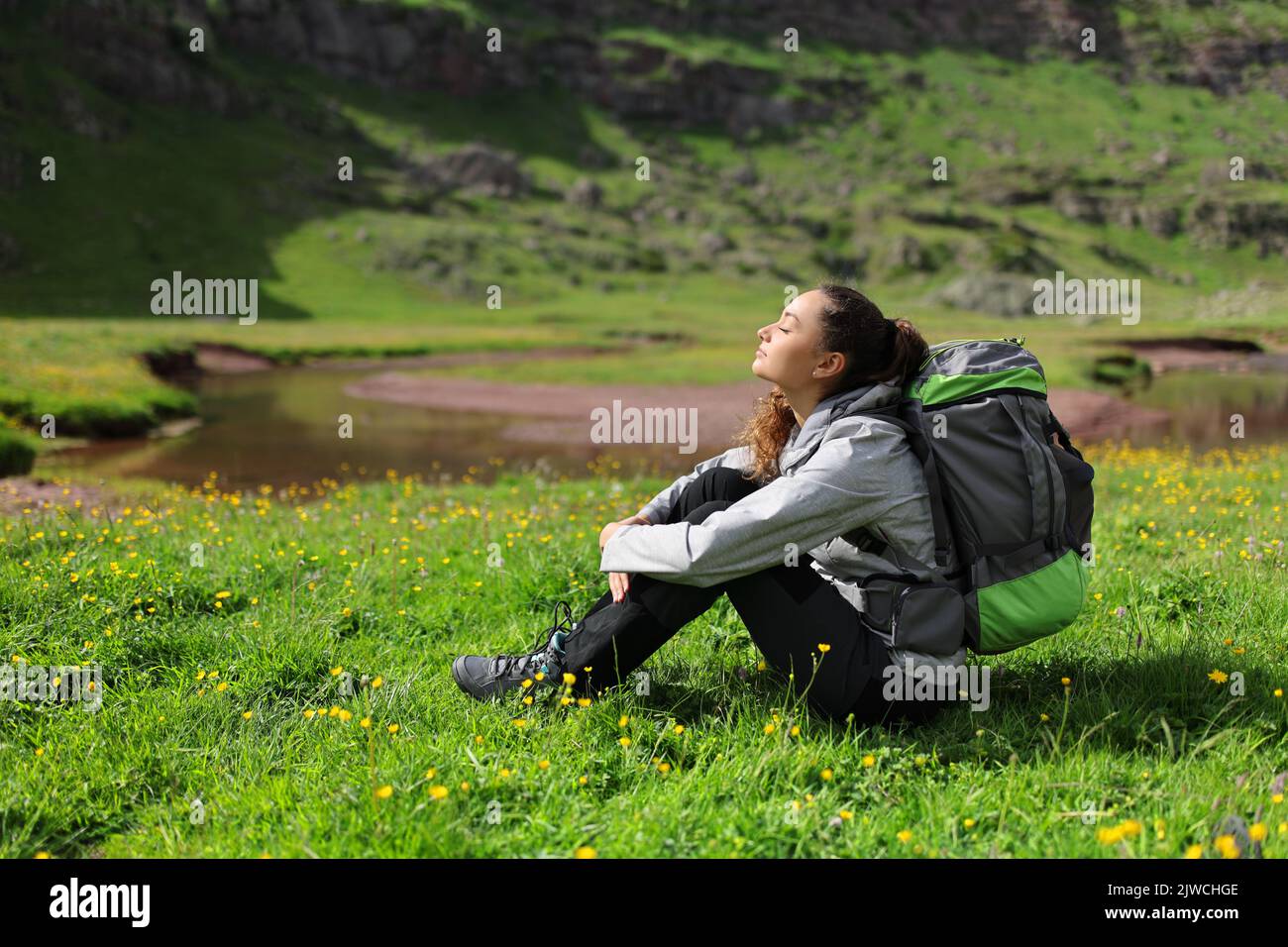 L'escursionista riposa e respira aria fresca seduto sull'erba in natura Foto Stock