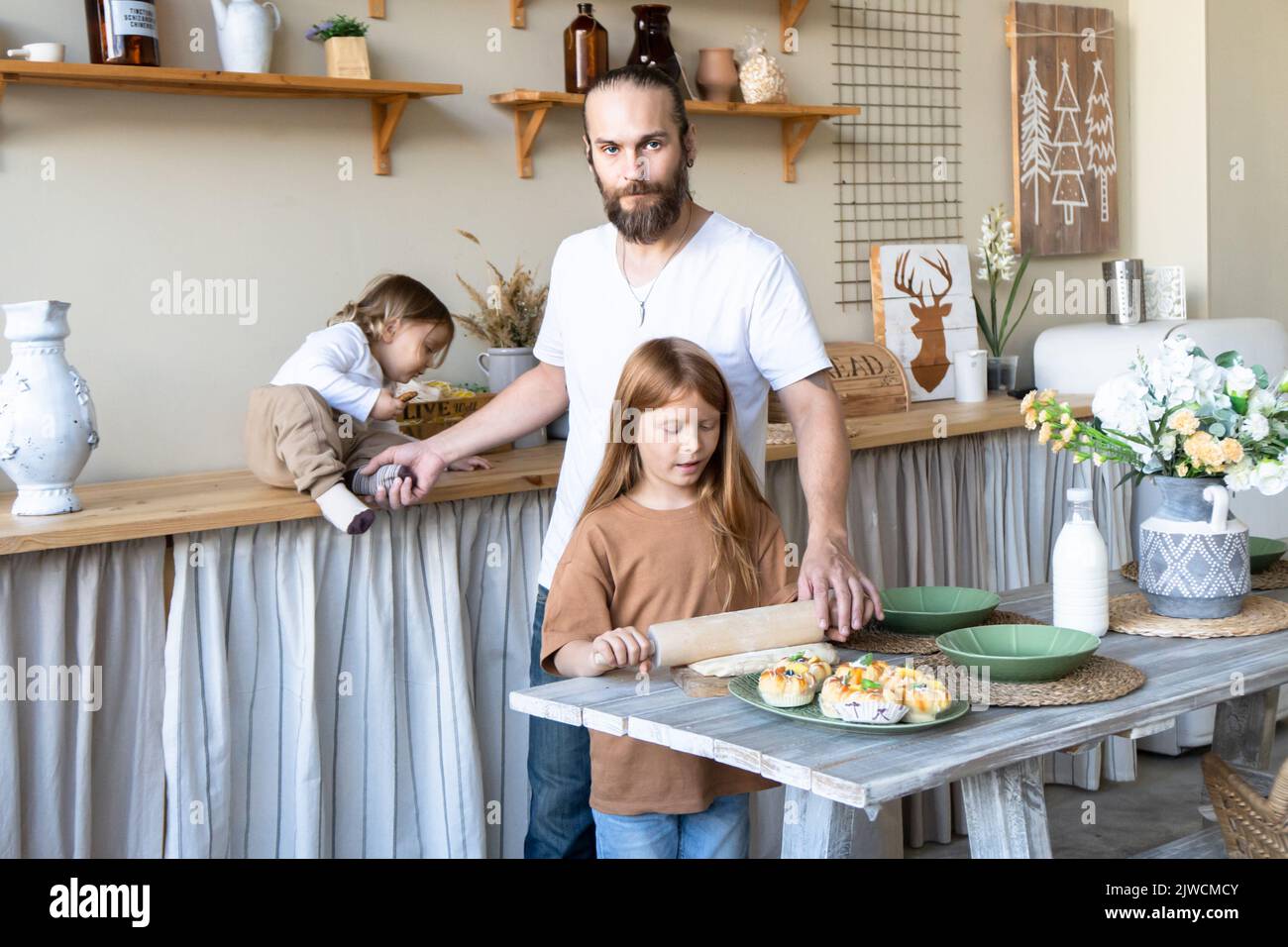 Una famiglia con tre bambini ha divertimento cuocere insieme.papà e figlia Laughing e cucinare cibo sano Vista anteriore concetto di stile di vita . Candidi Foto Stock