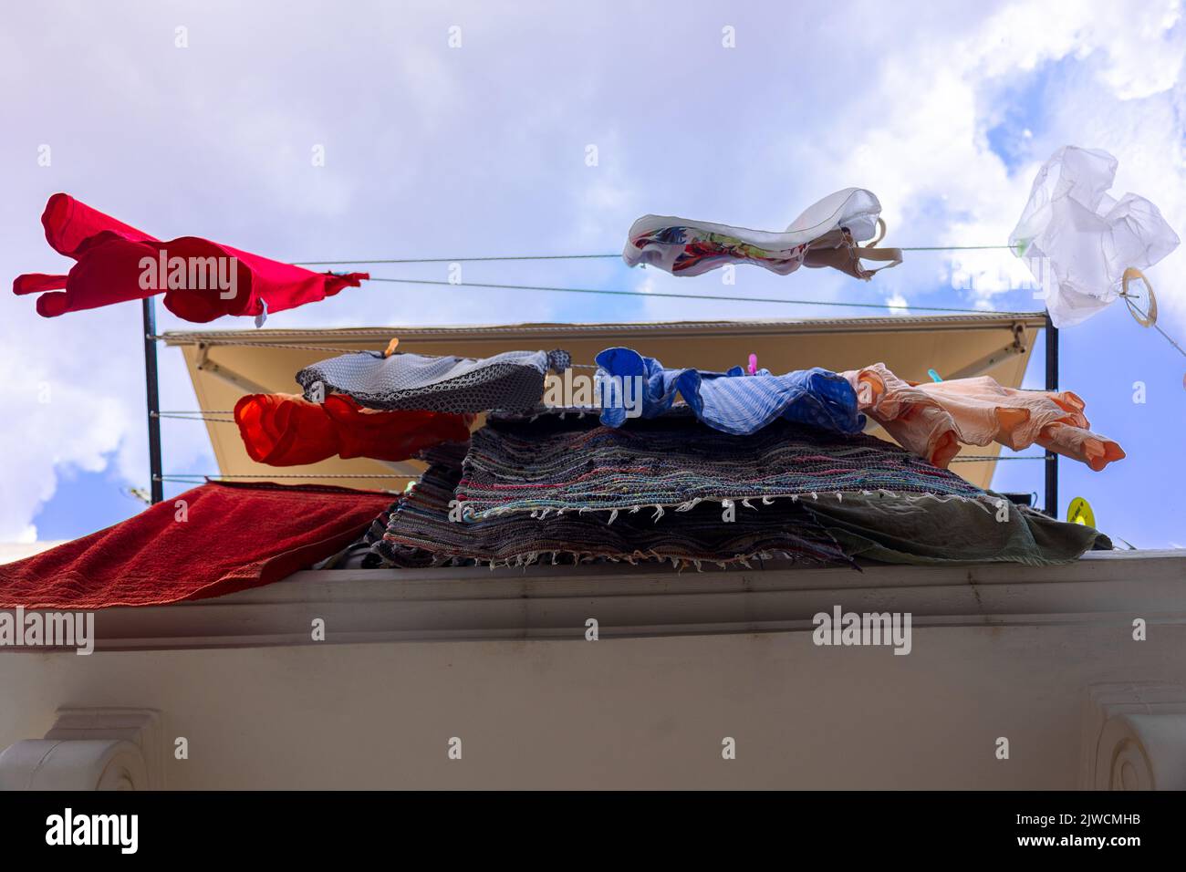 Colorato asciugamento di lino su clothesline nel villaggio di pescatori di Symi, isola in Grecia. Vista dal basso. Foto di alta qualità Foto Stock