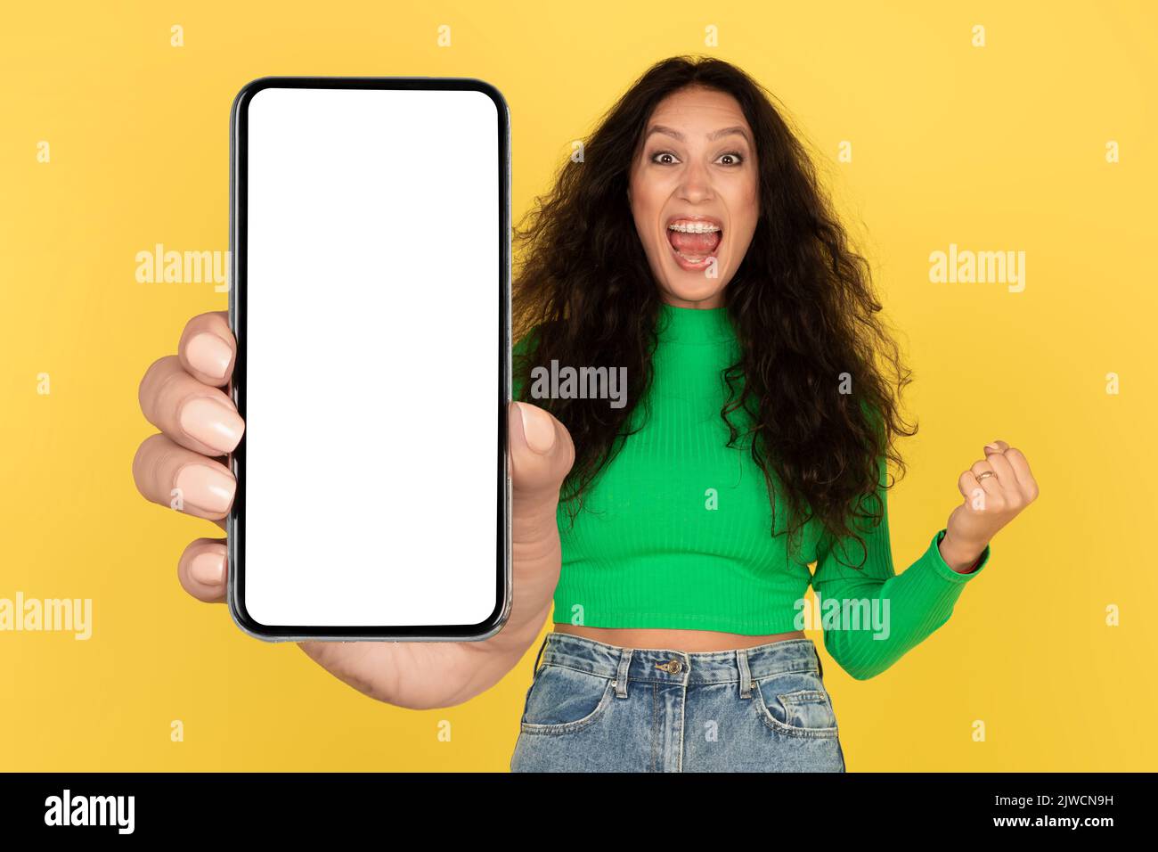 Emotivo Arabo Lady che mostra enorme schermo del telefono gesturing Sì, Studio Foto Stock