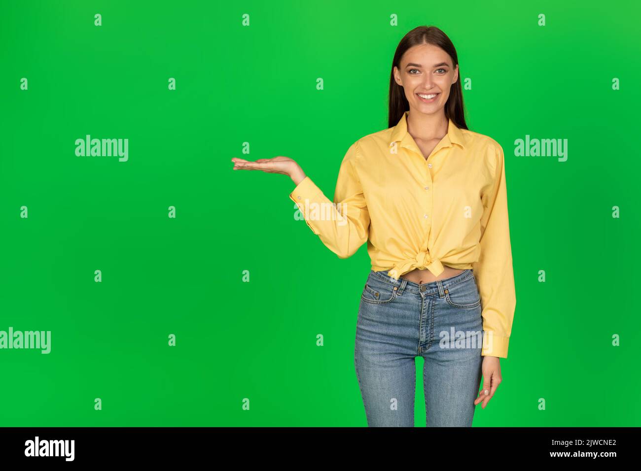 Happy Lady Holding oggetto invisibile sulla mano su sfondo verde Foto Stock