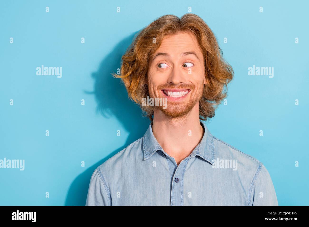 Foto dell'uomo astuto che indossa una camicia di denim che guarda spazio vuoto sorridendo sfondo di colore blu isolato Foto Stock
