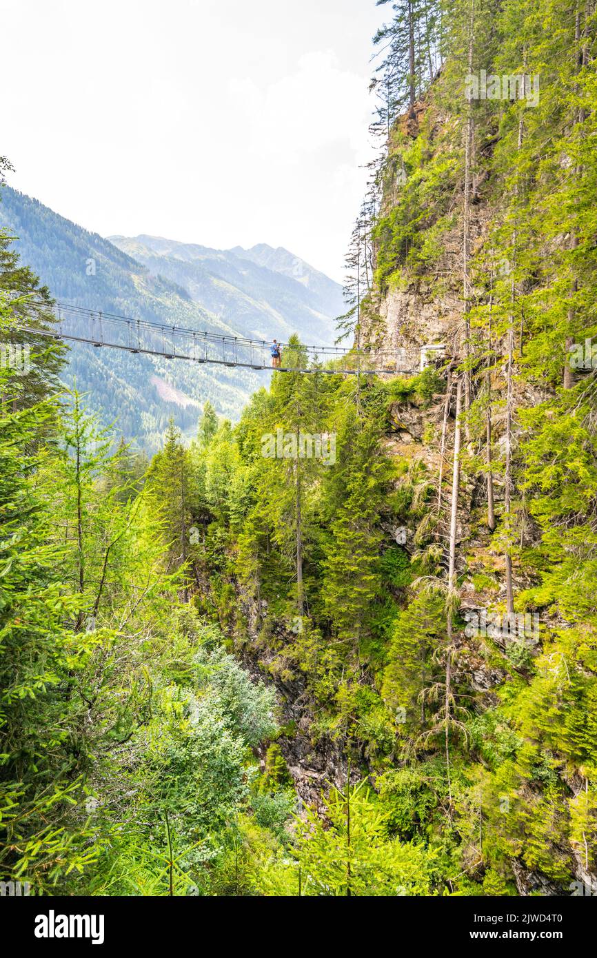 Semplice ponte sospeso sulla valle di montagna Foto Stock