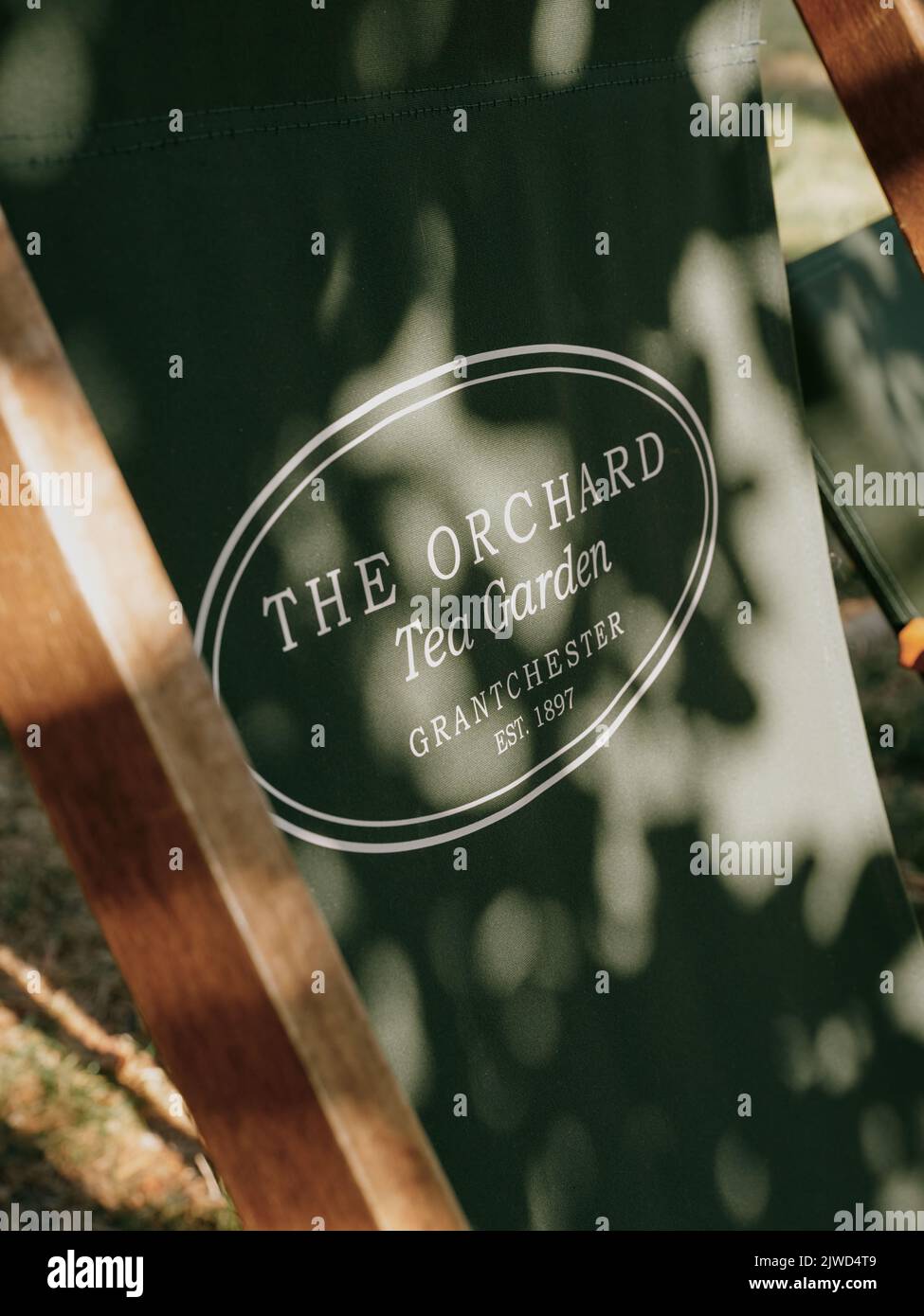 Posti a sedere all'aperto all'Orchard Tea Gardens con logo e luce appiccicata nel Grantchester Cambridge Cambridgeshire England UK Foto Stock