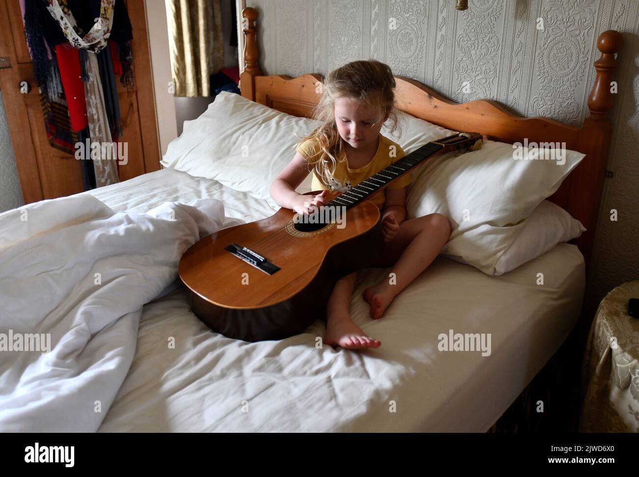 Giovane bambina che gioca con la chitarra acustica imparando musica musicista Foto Stock