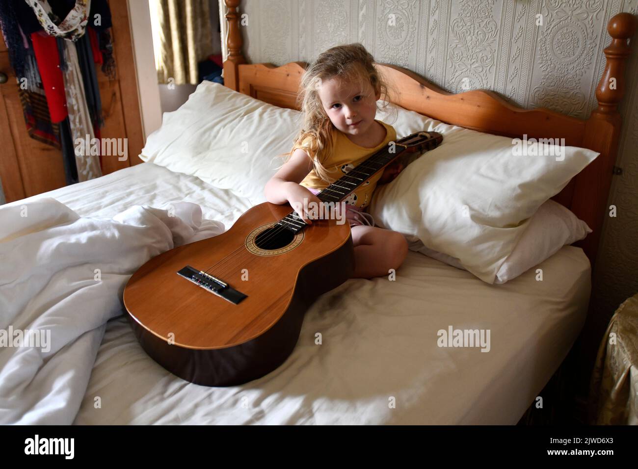 Giovane bambina che gioca con la chitarra acustica imparando musica musicista Foto Stock