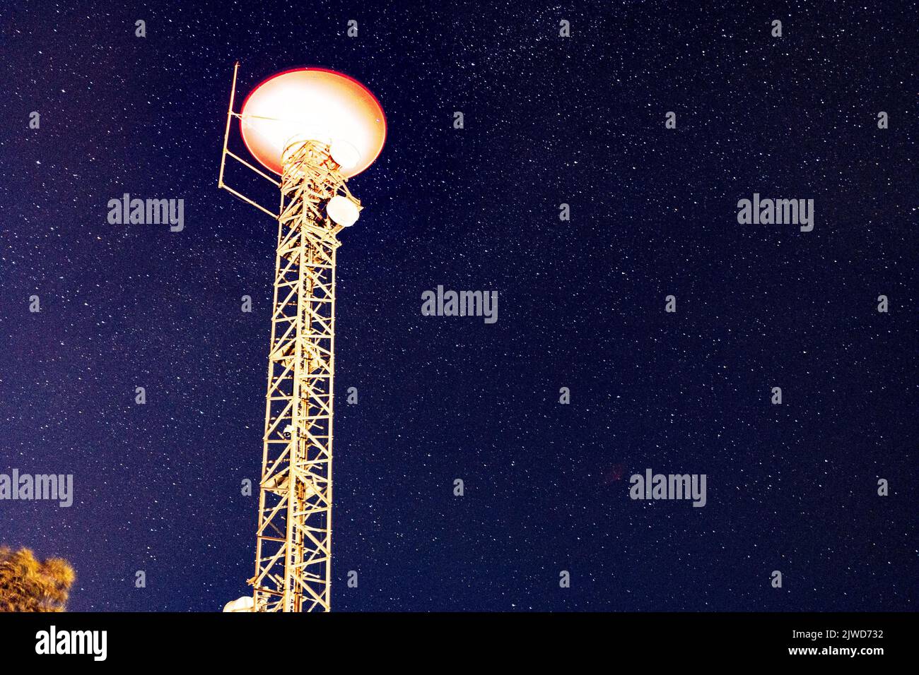 Una torre satellite illuminata contro il cielo stellato Foto Stock