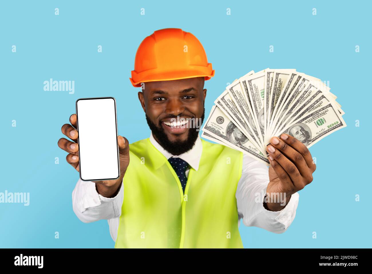 Ottima offerta. Black Builder Man dimostra denaro e smartphone vuoto alla fotocamera Foto Stock