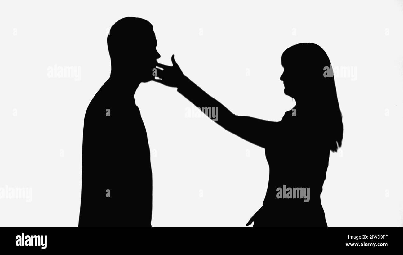 ombra di moglie che dà schiaffo al marito mentre litigare isolato su bianco Foto Stock