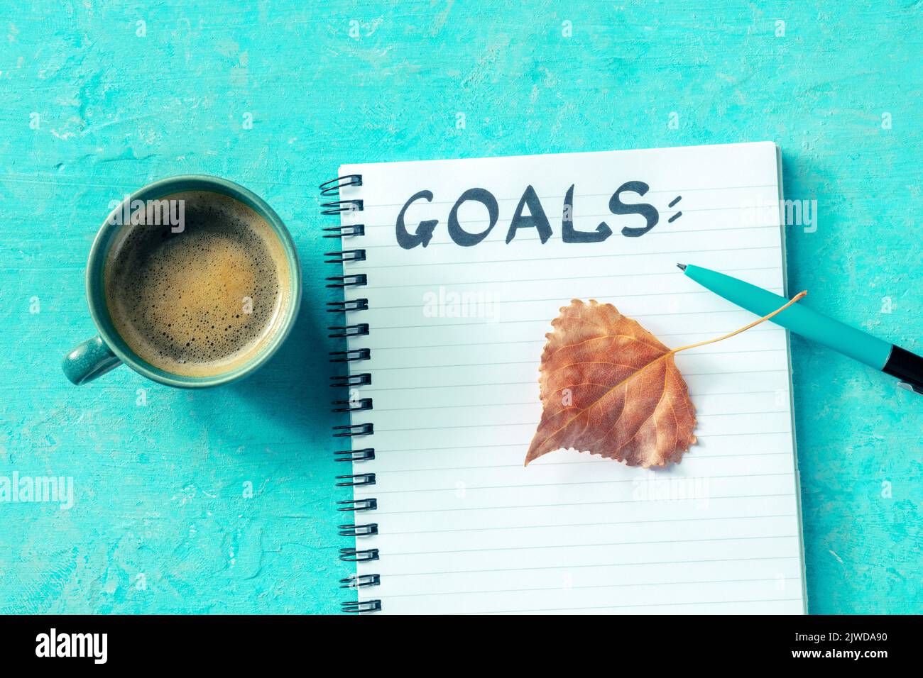 Programma per l'autunno. Gol, la parola manoscritta, con una foglia vibrante caduta, in un blocco note, overhead piatto stay shot con una tazza di caffè Foto Stock