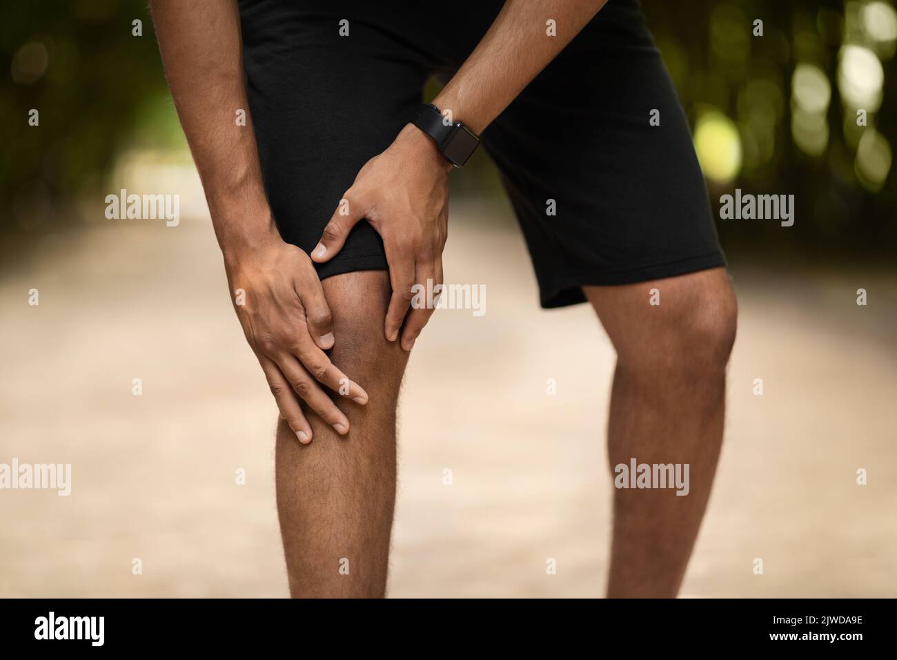 Corto di portsman che si esercita in parco pubblico, toccando caviglia ferita Foto Stock