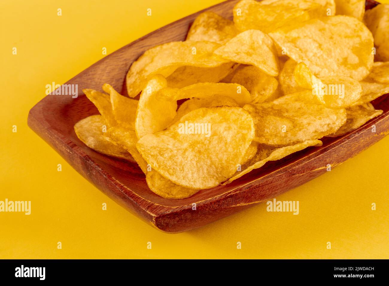 Patatine fritte o crocchette in una ciotola e sparse su sfondo giallo, un primo piano Foto Stock