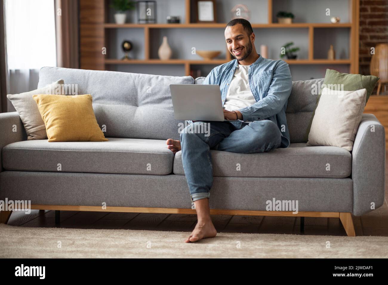 Concetto di freelance. Felice giovane uomo afroamericano che usa il laptop a casa Foto Stock