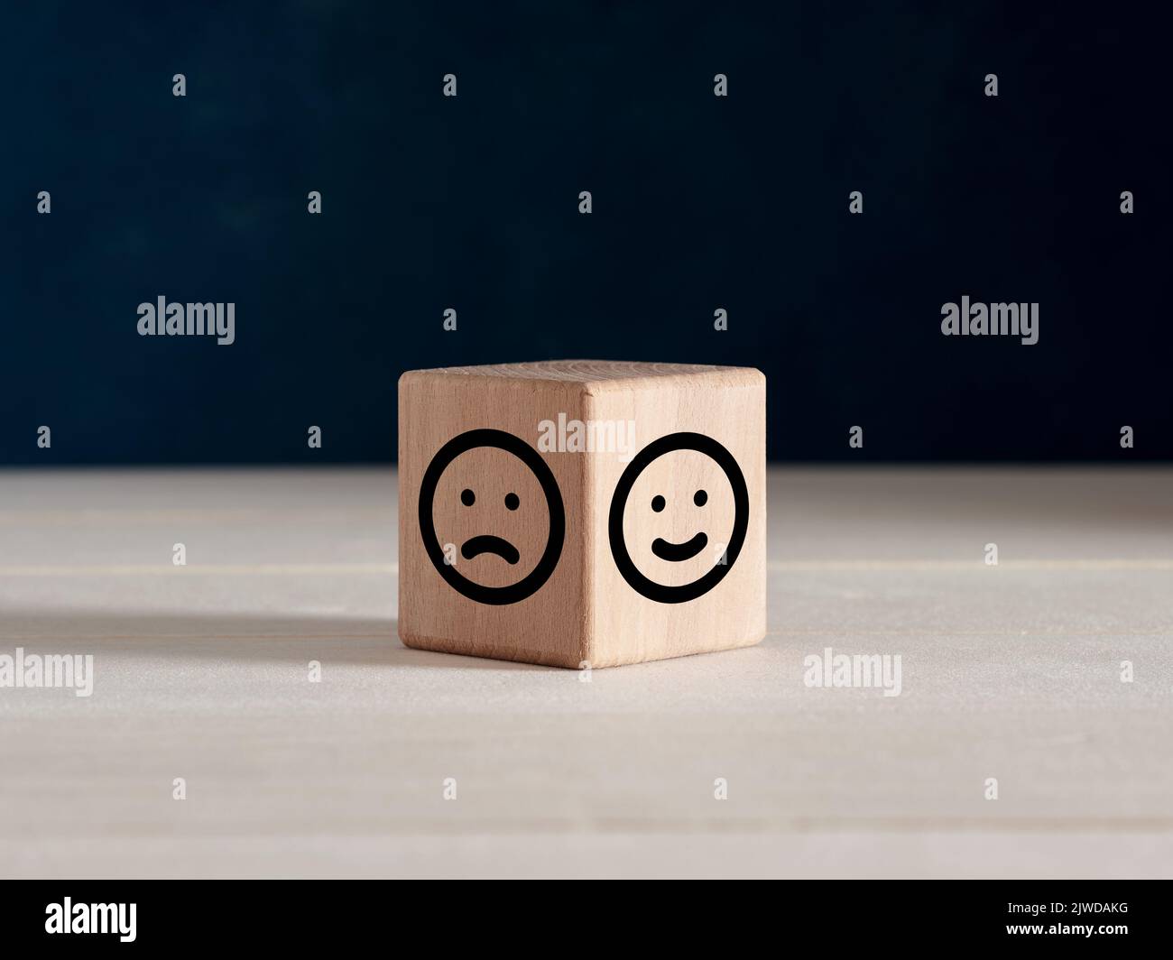 Mentalità positiva o negativa o concetto di soddisfazione del cliente. Facce emoticon felici e tristi su cubo di legno. Foto Stock