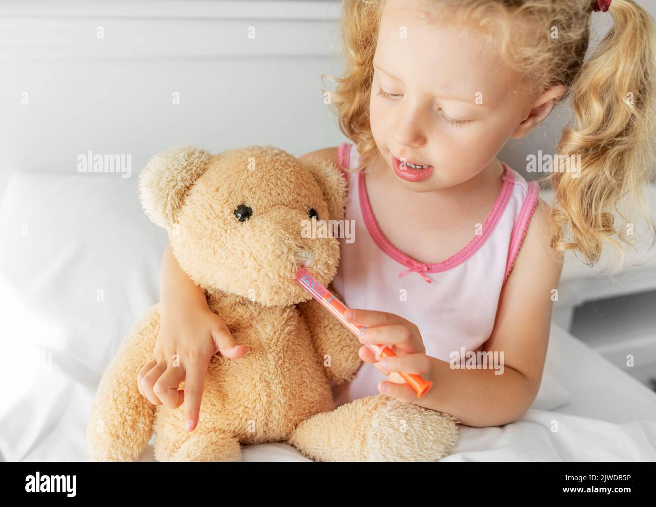 Il bambino tratta l'orso. Gioca durante la malattia. Foto Stock