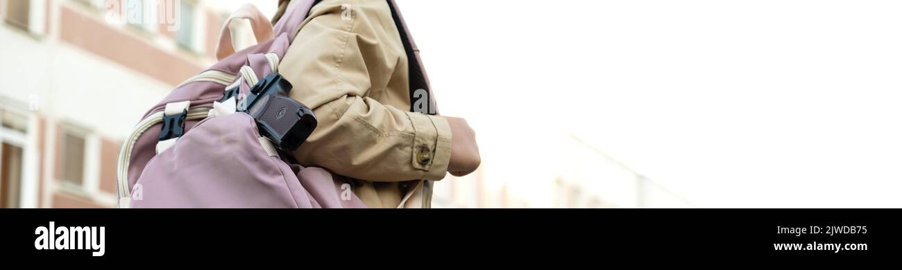 Armi da fuoco a scuola. Scolaretta con una pistola in uno zaino su un background scolastico. La ragazza porta una pistola a scuola. Violenza scolastica. Foto Stock