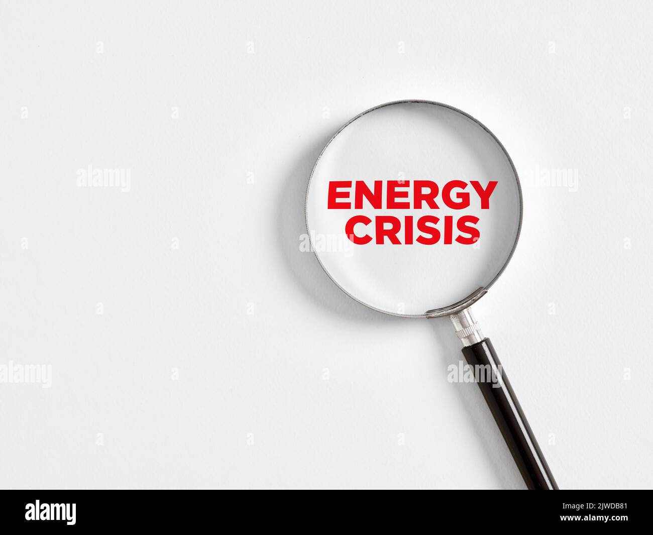 Analizzare o concentrarsi sul concetto di problema di crisi energetica. La lente d'ingrandimento ingrandisce la parola crisi energetica su sfondo bianco. Foto Stock