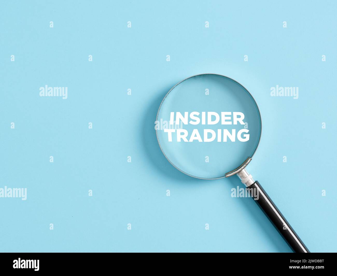 Lente di ingrandimento con il testo insider trading su sfondo blu. Concetto aziendale. Foto Stock