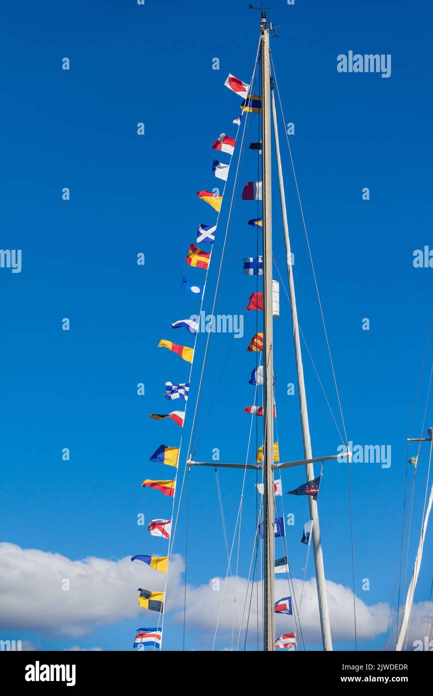 Una collezione di bandiere internazionali che volano da un albero di una barca a vela classica Foto Stock