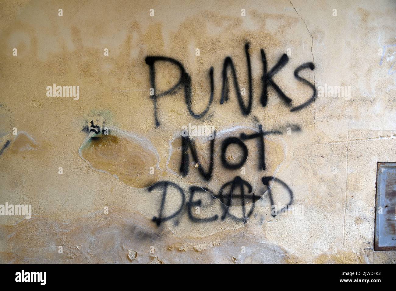 Punks non Dead Anarchy o slogan anarchico o Graffiti sulla vecchia parete degradata o facciata danneggiata Foto Stock