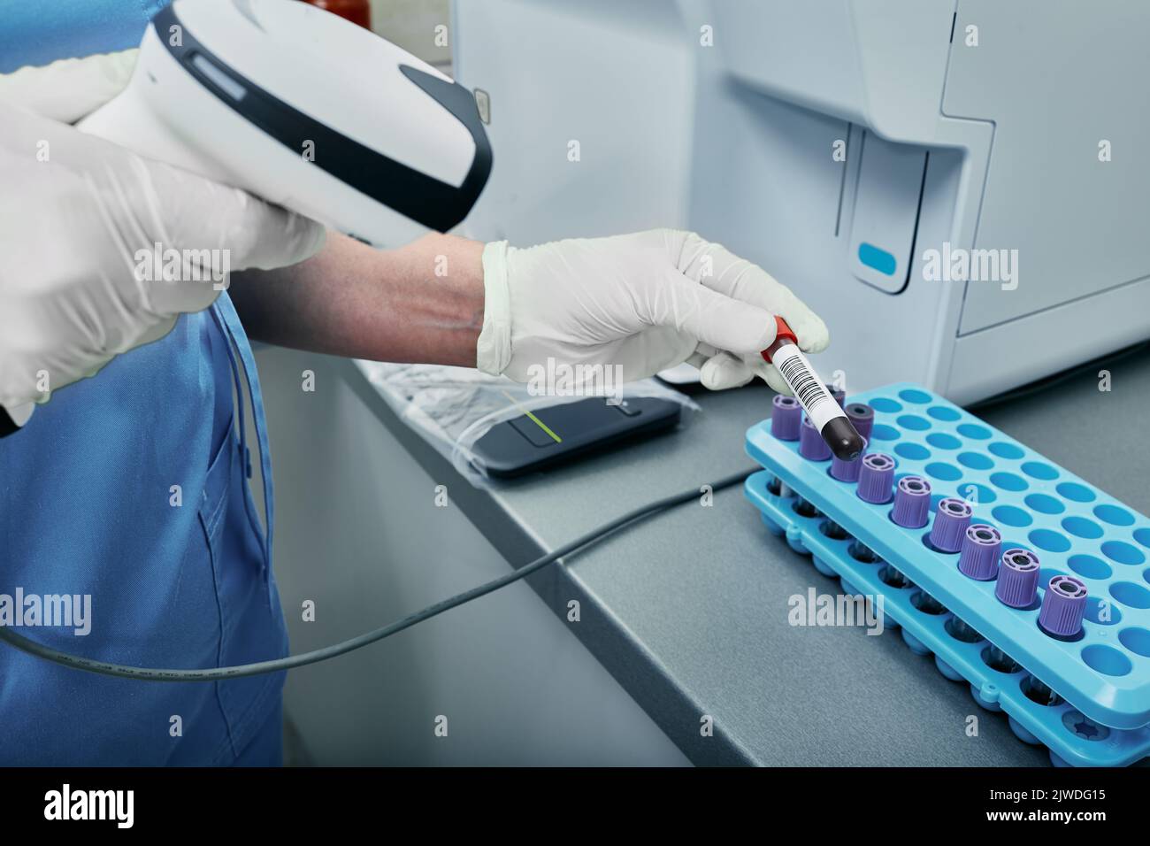 Tecnico di laboratorio che esegue la scansione del codice a barre della provetta con sangue. Etichetta con codice a barre sulla provetta per il tracciamento dei campioni di sangue Foto Stock