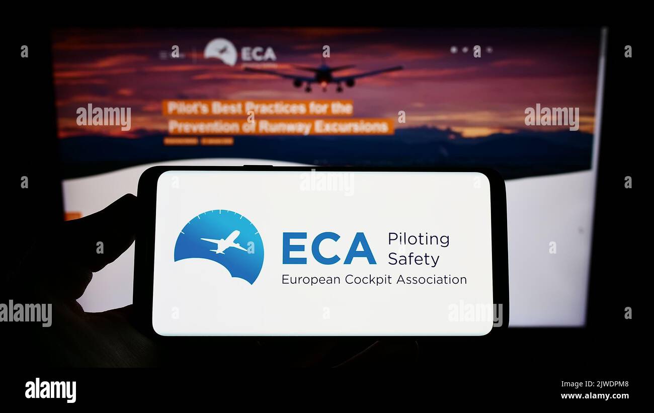 Persona che tiene uno smartphone con il logo dell'organizzazione European Cockpit Association (ECA) sullo schermo di fronte al sito Web. Messa a fuoco sul display del telefono. Foto Stock