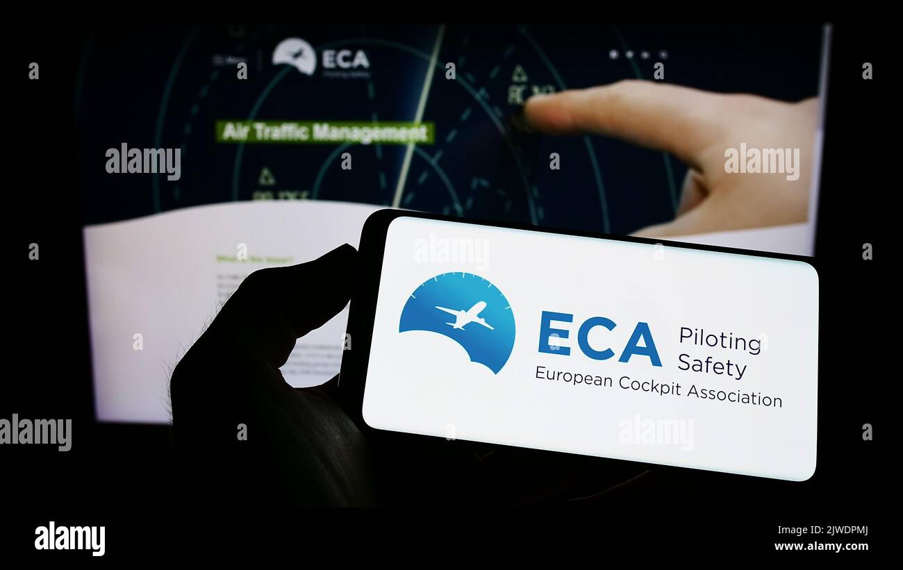 Persona che tiene un telefono cellulare con il logo dell'organizzazione European Cockpit Association (ECA) sullo schermo di fronte alla pagina web. Messa a fuoco sul display del telefono. Foto Stock