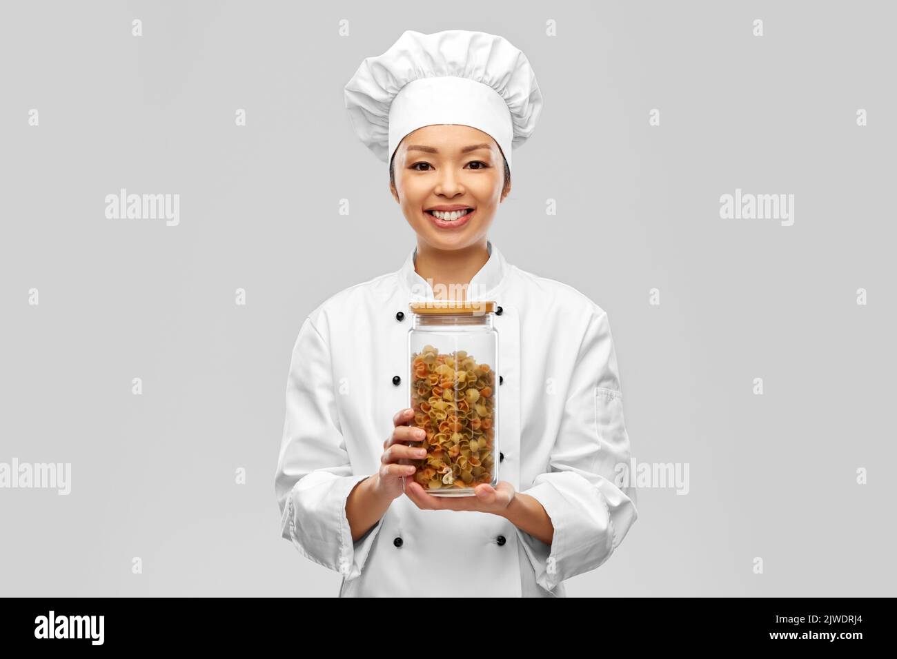 sorridente cuoco femmina che tiene barattolo con pasta Foto Stock