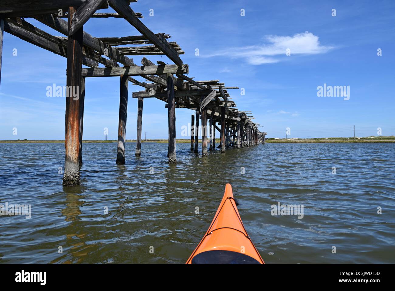In kayak si passa davanti ai resti di piloni di un ponte di legno degli anni '30 che attraversa il Pamlico Sound nel Pea Island Wildlife Refuge, Outer Banks, North Carolina Foto Stock