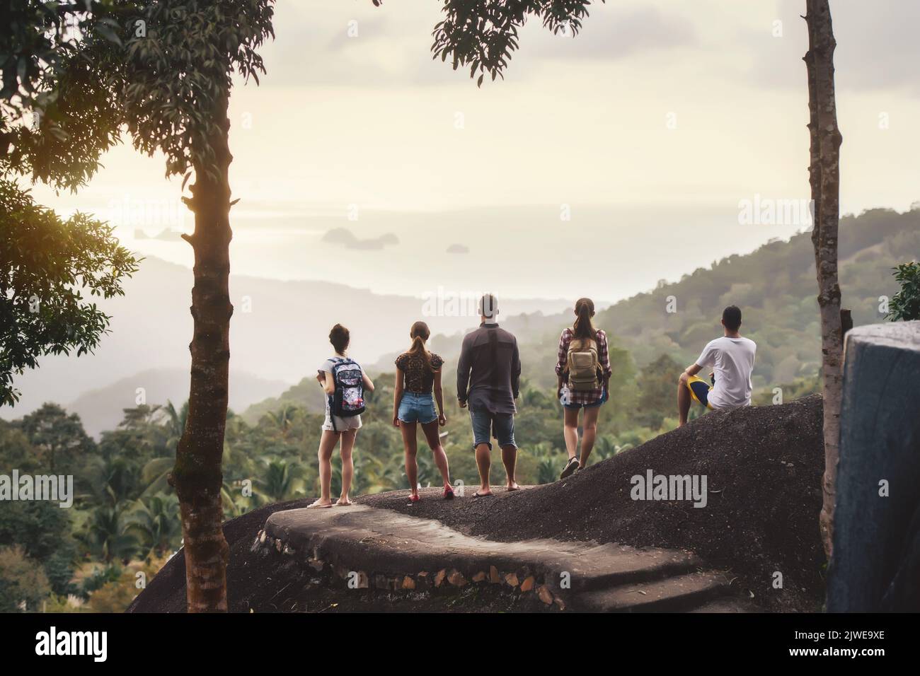 Gruppo di giovani turisti si trova al punto di vista della giungla e guarda al tramonto. Isola di Samui, Thailandia Foto Stock