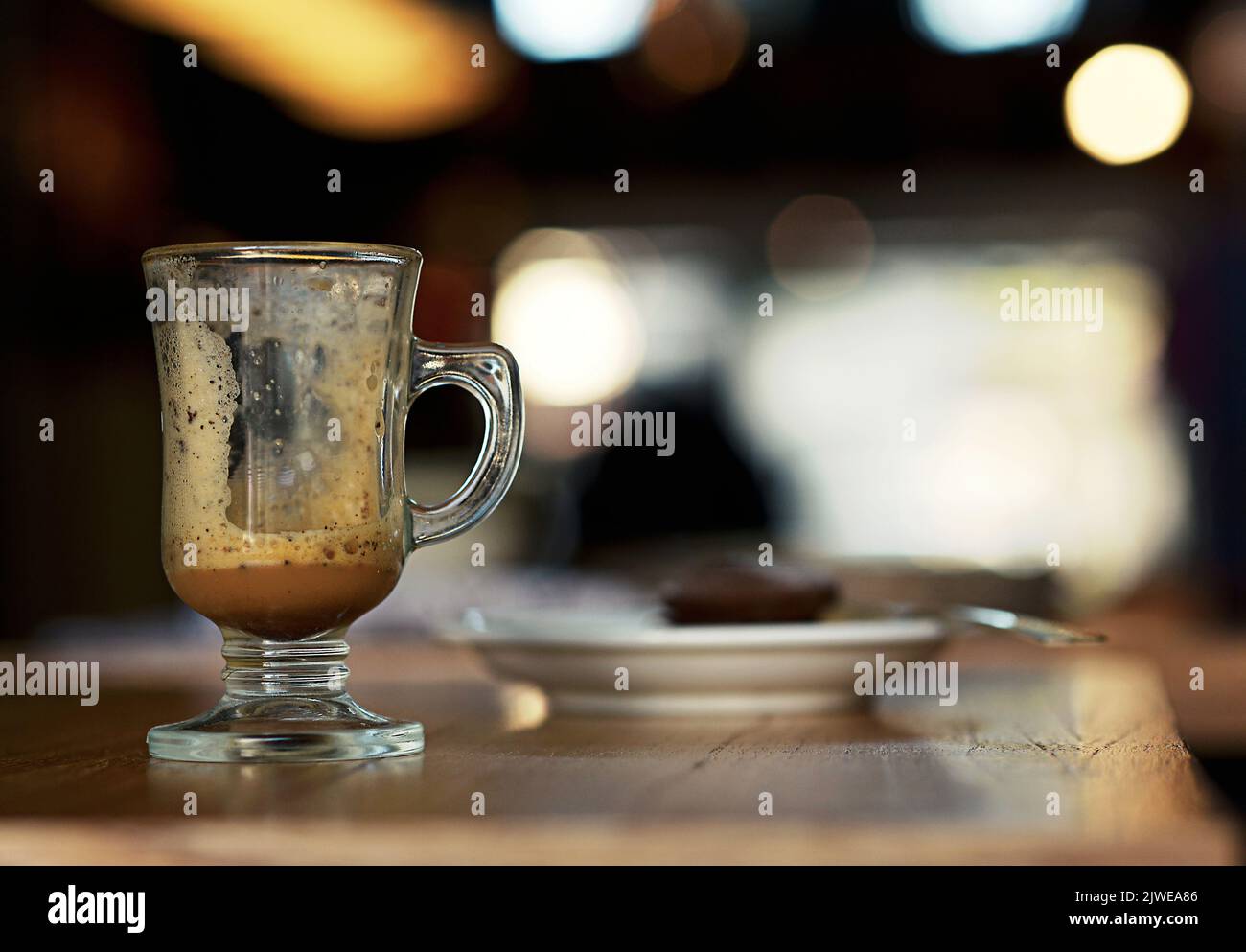 Primo piano di una tazza vuota di caffè su un tavolo e di una fetta di torta al cioccolato su un piatto Foto Stock