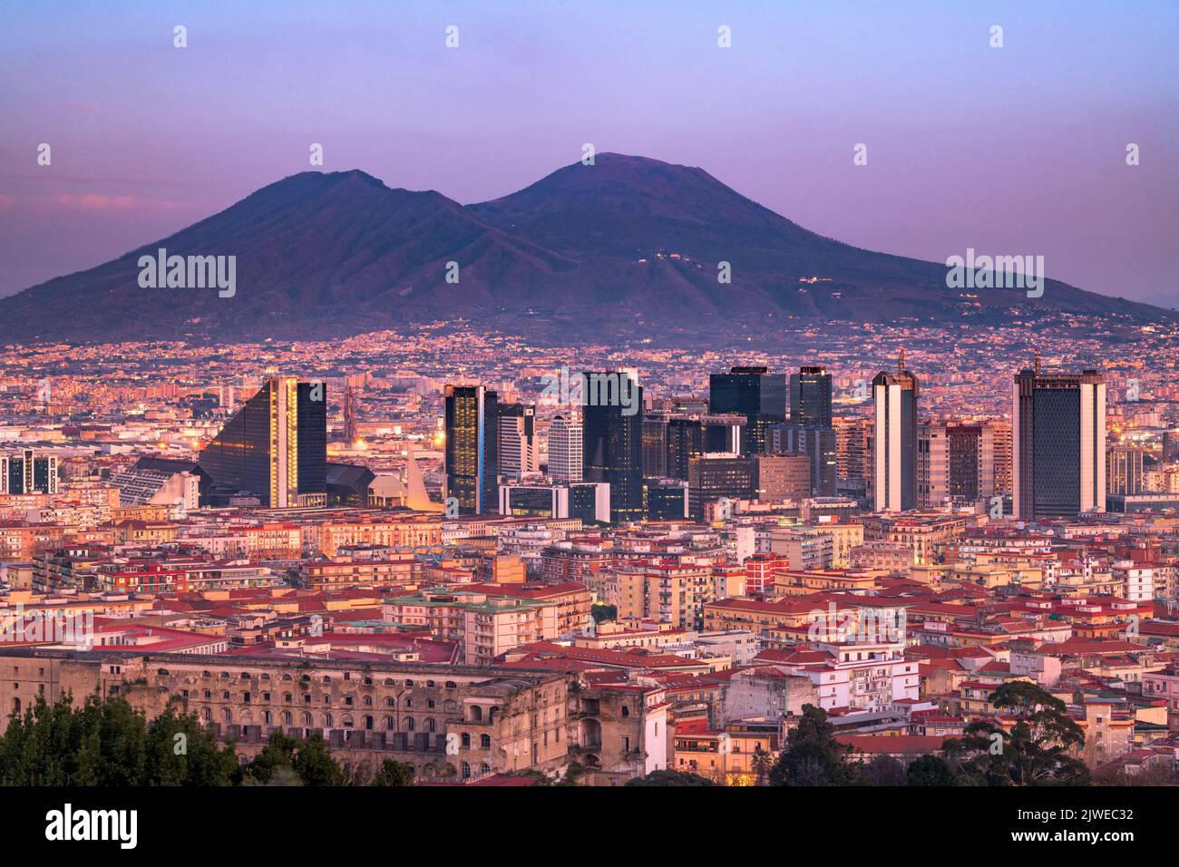 Napoli, Italia con lo skyline del quartiere finanziario sotto il Monte Vesuvio al crepuscolo. Foto Stock
