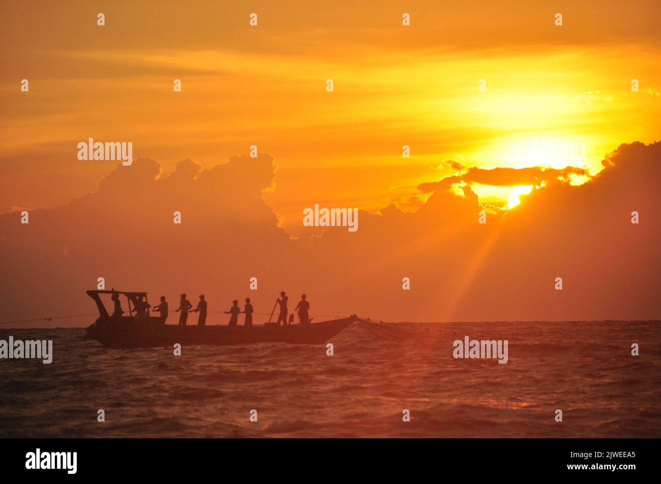 Silhouette di pescatori che navigano in una tradizionale barca da pesca al tramonto, Ampenan Beach, Lombok, Indonesia Foto Stock