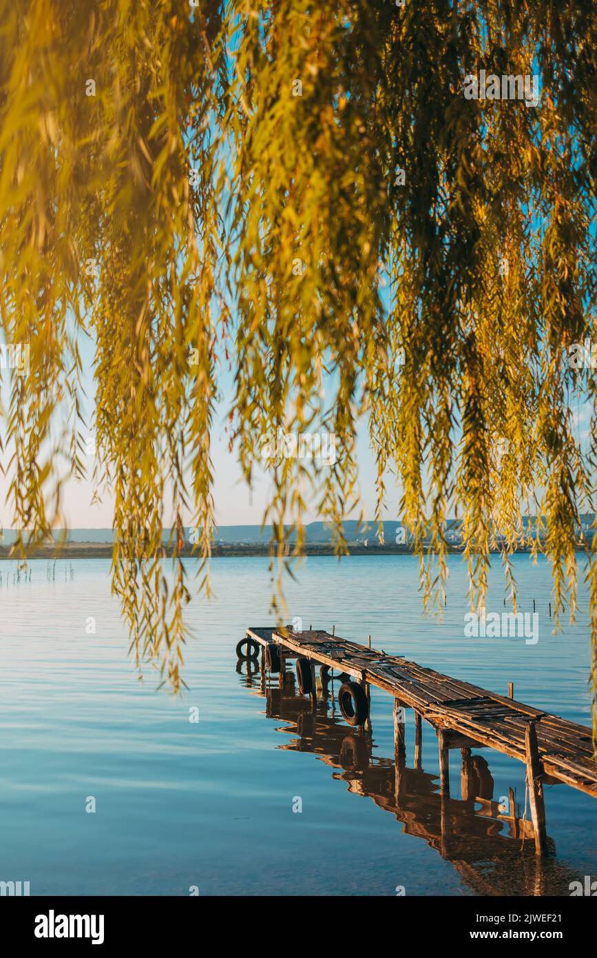 Tramonto sul lago di mare e vecchio molo in legno, romantica destinazione di viaggio, paesaggio naturale Foto Stock