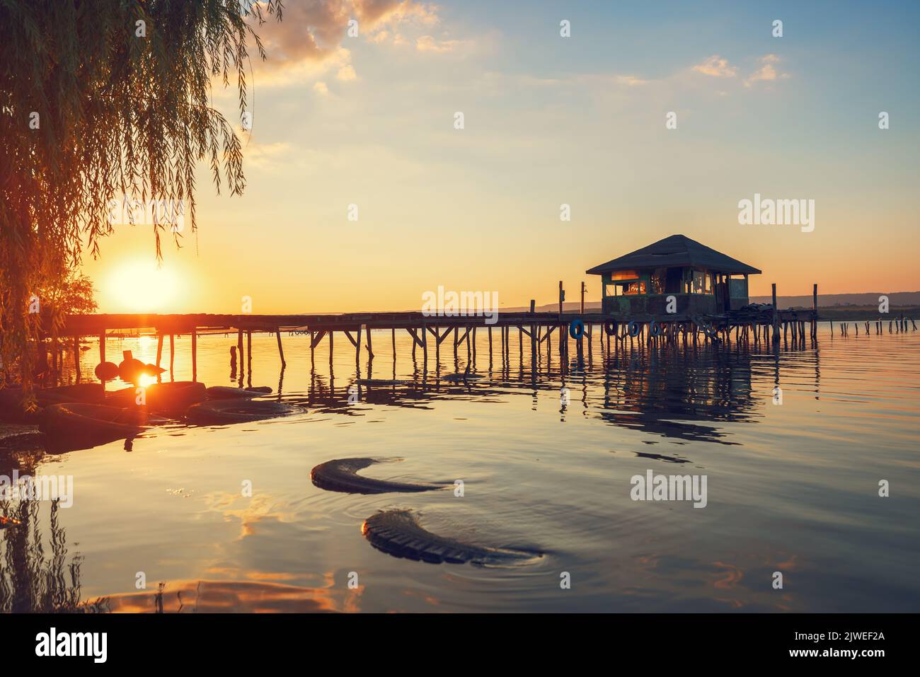 Tramonto sul lago di mare e vecchio molo in legno, romantica destinazione di viaggio, paesaggio naturale Foto Stock