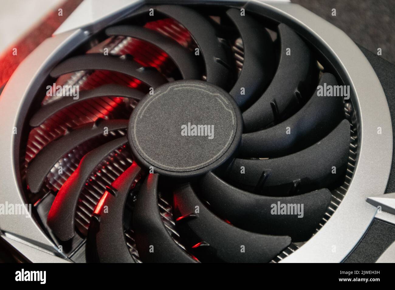 Ventola più fredda sulla scheda video grafica GPU, primo piano in luce rossa con messa a fuoco selettiva, dettagli hardware del PC. Componenti da computer per giochi o cripto Foto Stock