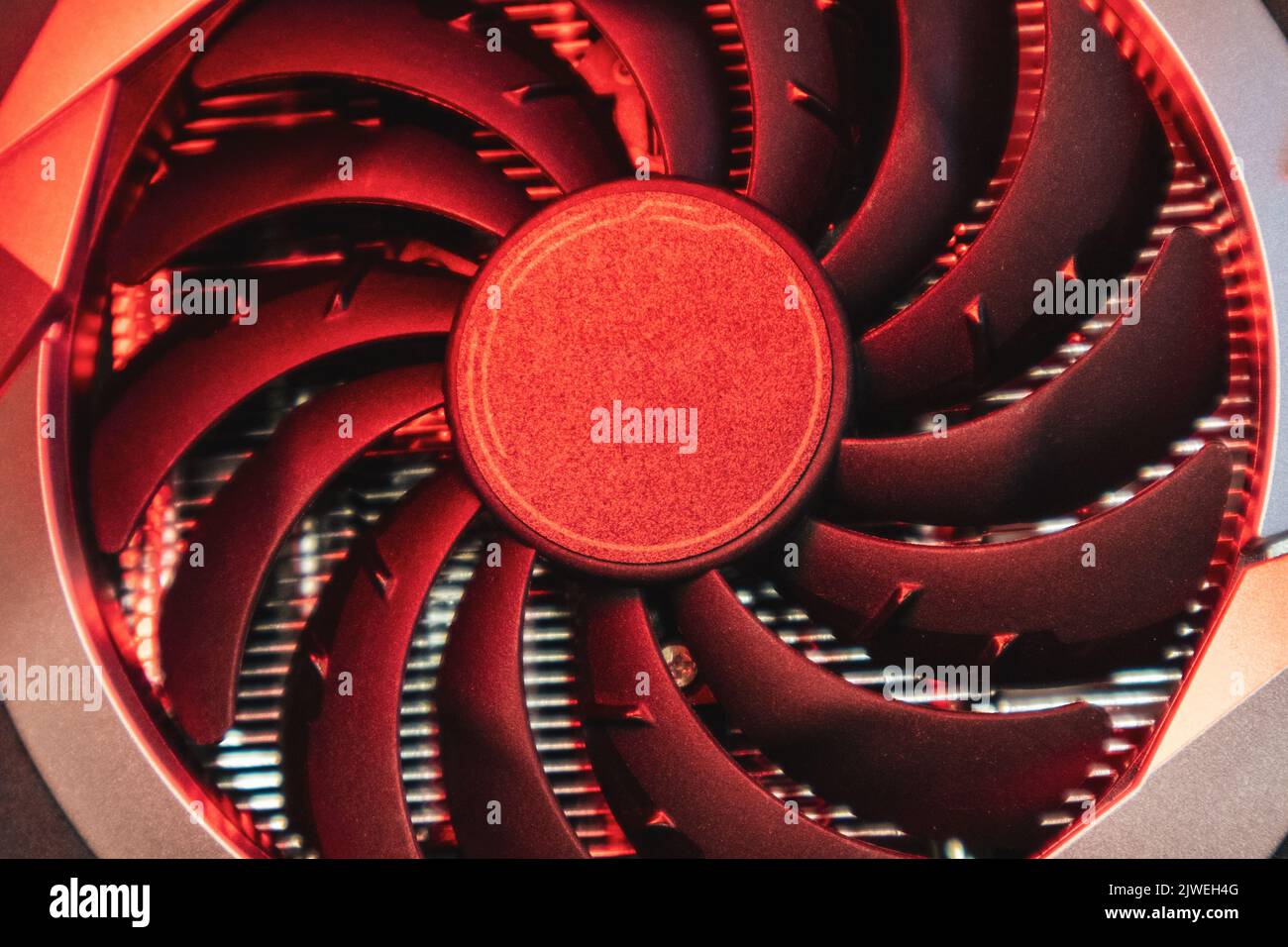 Ventola più fredda sulla scheda video grafica GPU, primo piano con luce rossa brillante, dettagli hardware del PC. Componenti del sistema di raffreddamento del calcolatore Foto Stock