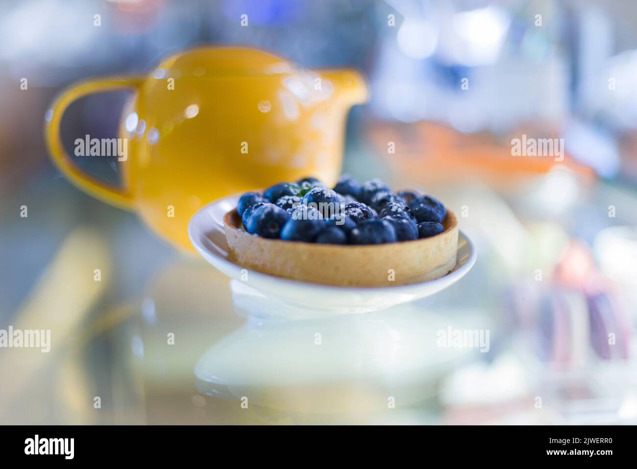 Una crostata di mascarpone con mirtilli e bollitore da tè giallo sullo sfondo Foto Stock
