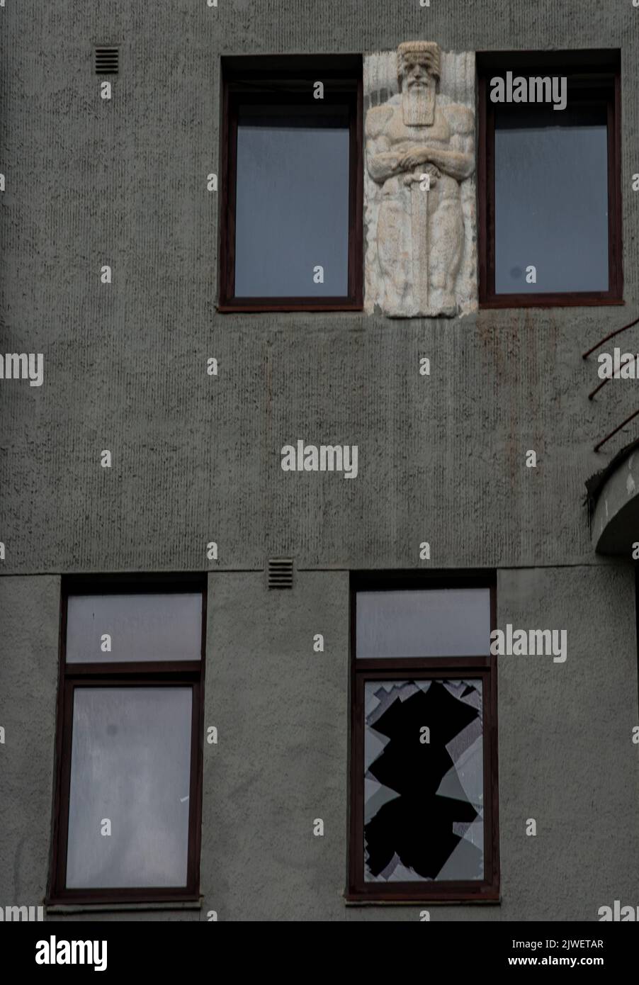 Vista su un edificio di Kharkiv, con un bassorilievo di un guerriero, e una finestra rotta, a seguito di un attacco missilistico russo Foto Stock